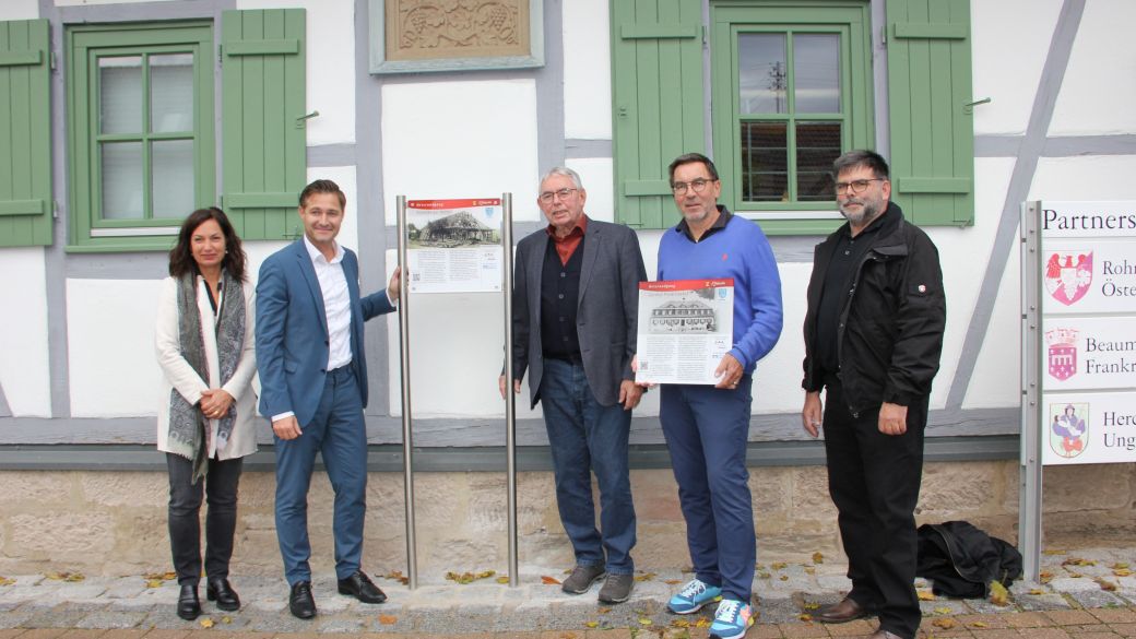  – BM Björn Steinbach und BM a.D. Harry Murso enthüllen die erste Tafel an der Eichelberger Kelter. Daneben Ortsvorsteherin Pamela Grimm-Baumann, Steffen Kappes (2.v.r.) und Thomas Kugler, Mitglieder der Arbeitsgruppe.